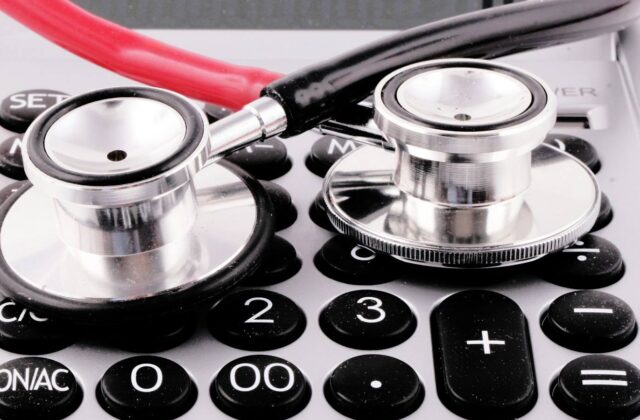 A medical billing statement and pen on a desk beside a calculator