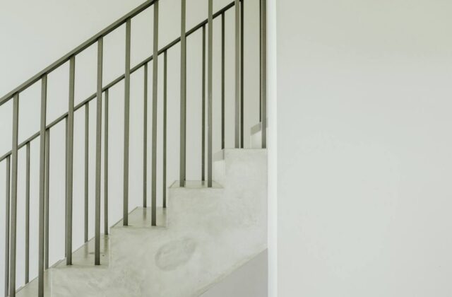 A concrete apartment stairwell with a metal handrail seen from below