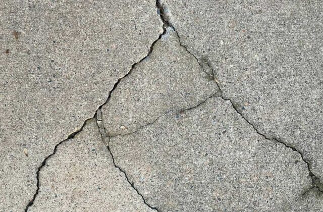 Concrete sidewalk lifted and cracked by tree roots on a residential street