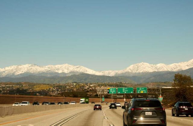 Freeway interchange near Sylmar with trucks in the lanes and the San Gabriel Mountains behind