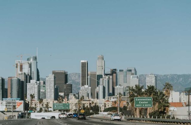 Busy boulevard in Van Nuys with traffic signals, storefronts and the 405 freeway overpass in the distance