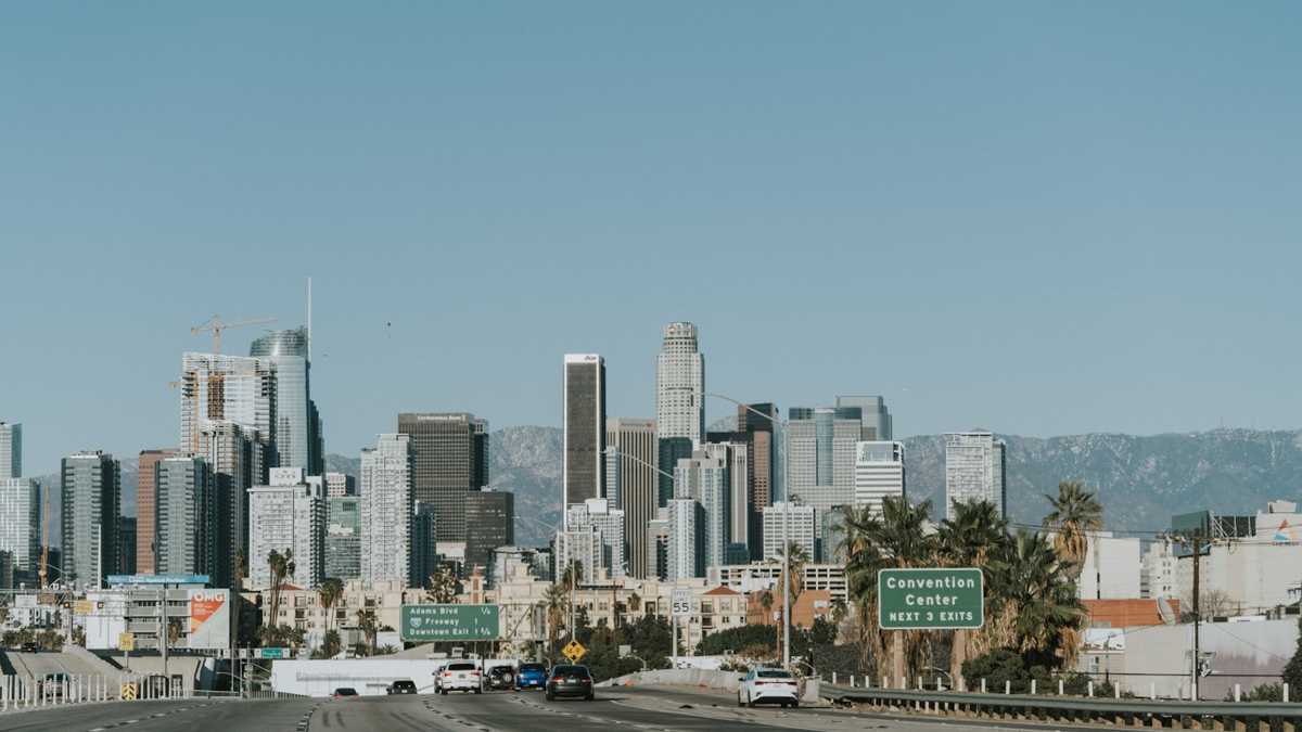Busy boulevard in Van Nuys with traffic signals, storefronts and the 405 freeway overpass in the distance
