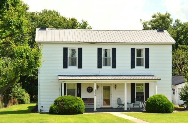 Two-story white house with black shutters and a front porch on a lawn