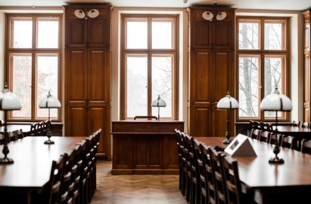 Empty wood-paneled meeting room with long wooden tables, chairs and lamps