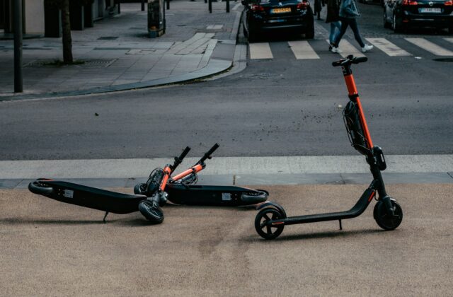 Rental electric scooters lying tipped over near a city road crosswalk