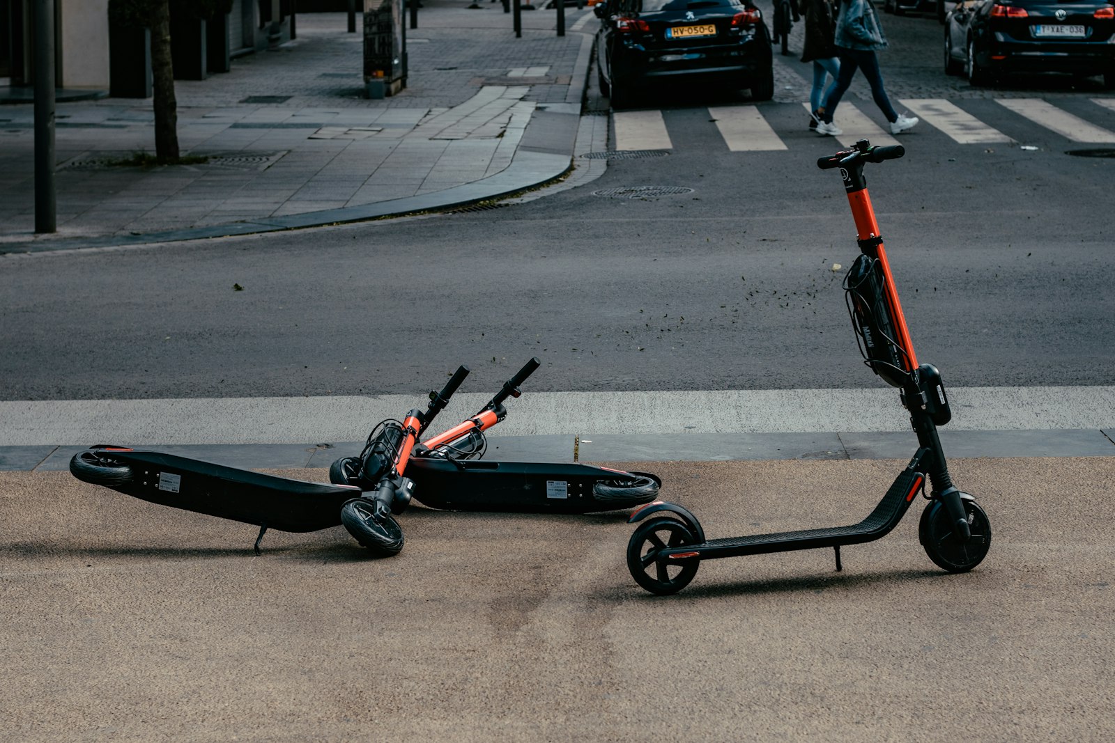 Rental electric scooters lying tipped over near a city road crosswalk