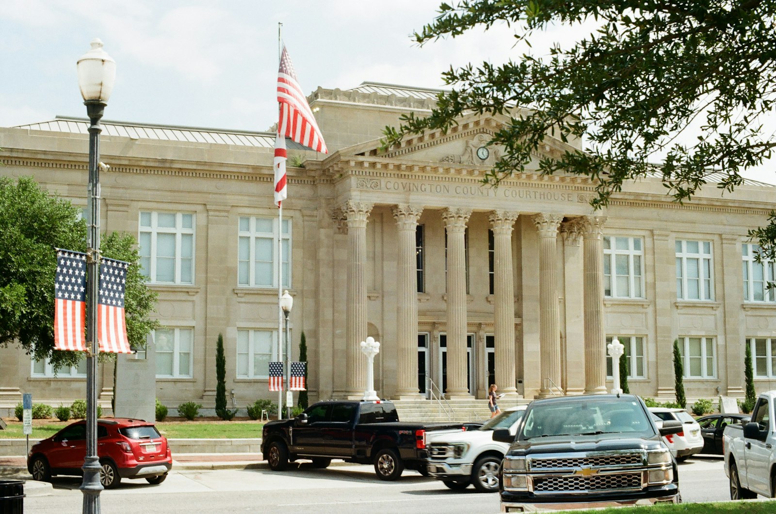 Classical government building with columns and American flags beside parked cars