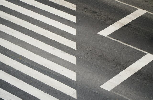 White and black pedestrian crosswalk stripes painted across an asphalt road