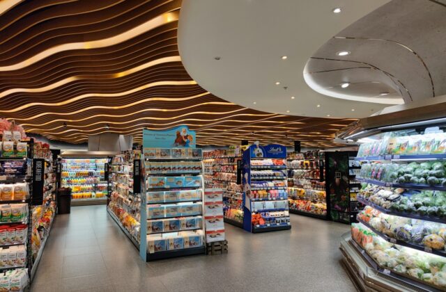 Supermarket interior with product shelves beneath a wavy wooden ceiling