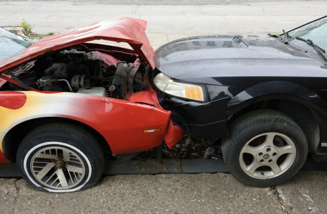 Red and black cars with crushed front ends after a head-on collision