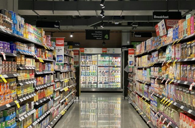 Grocery store aisle with fully stocked shelves and refrigerated cases
