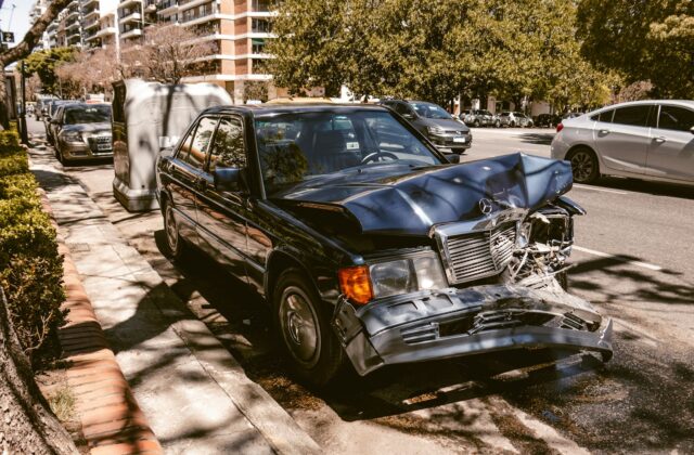 Damaged car sitting on the side of a city road