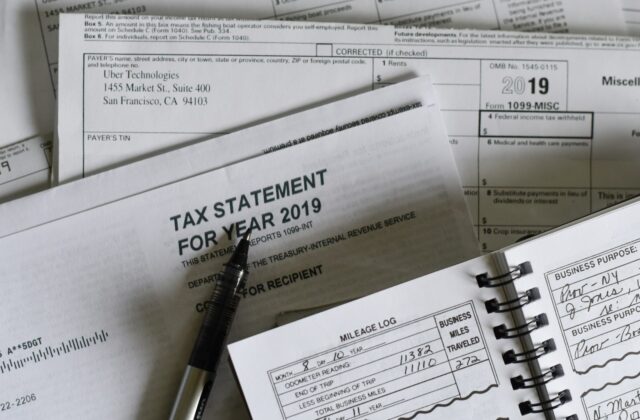 Pen resting on tax forms and a mileage log book