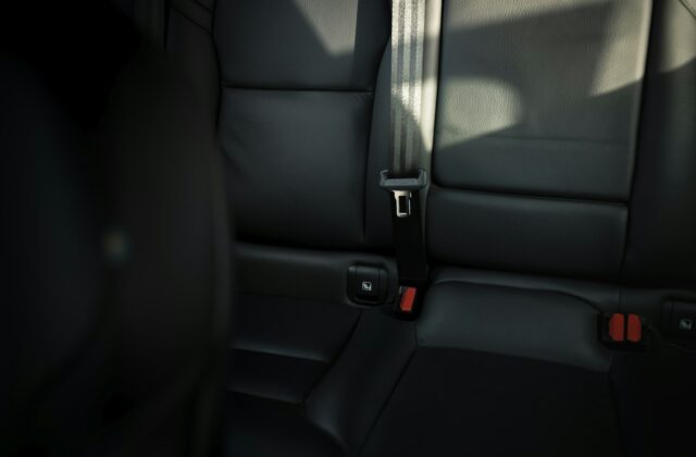 Black leather rear car seat with seat belt buckled across it